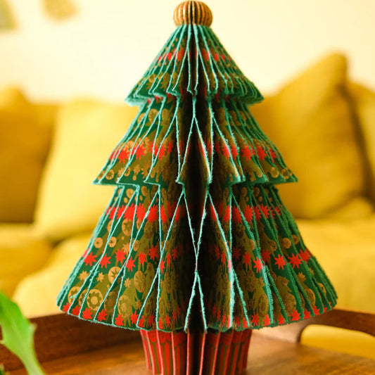 Decorative Christmas tree made of green paper with red patterns on a wooden table.