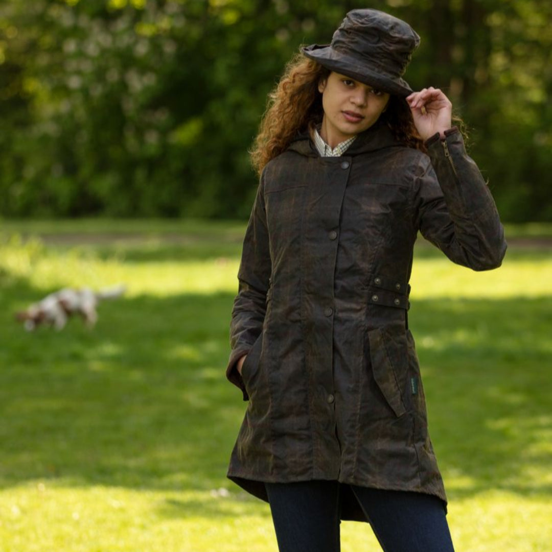 A woman wearing a hooded wax jacket in a honey-toned plaid design pattern