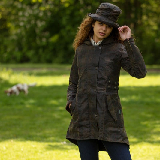 A woman wearing a hooded wax jacket in a honey-toned plaid design pattern